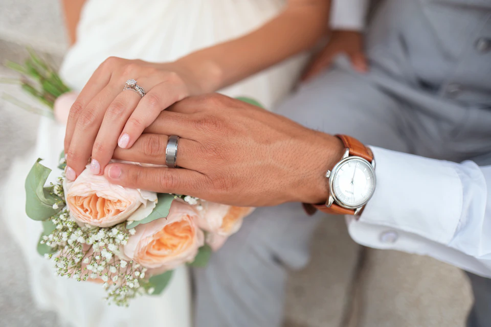 Hände mit Ringen über dem Bouquet